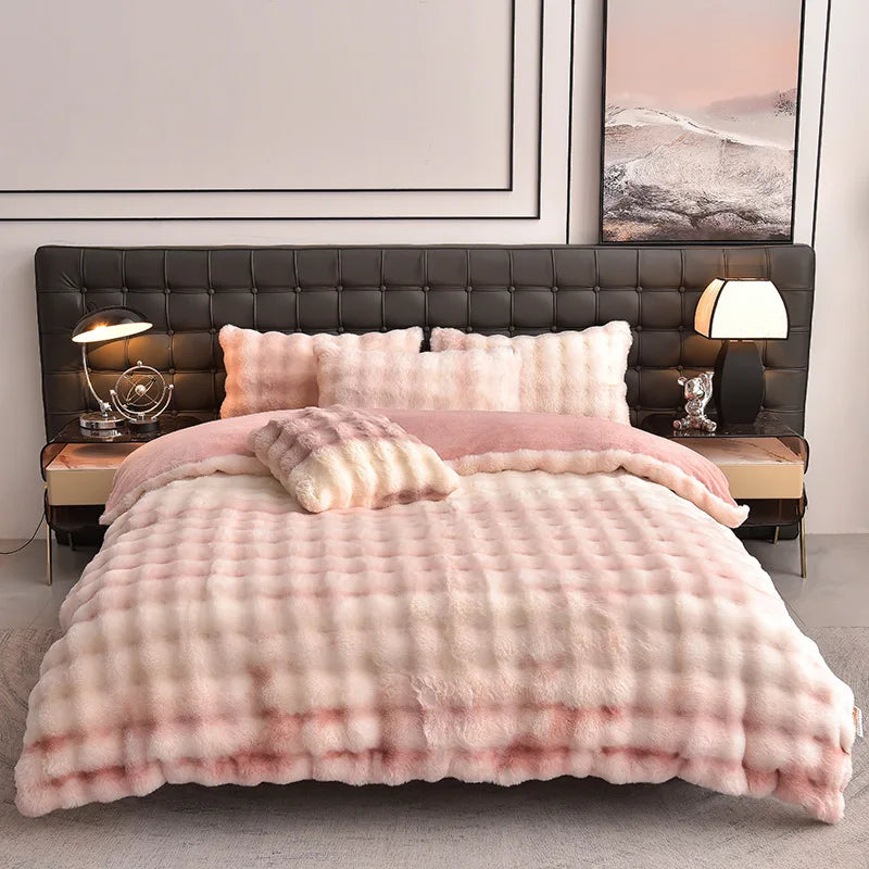 A pink plush rabbit hair bedding set with a quilted duvet and pillows displayed on a dark upholstered bed.