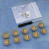 A silver metal button pin is shown resting on a white cloth with other similar pins.