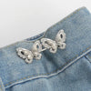 Silver butterfly clip brooch pinned onto a blue denim fabric
