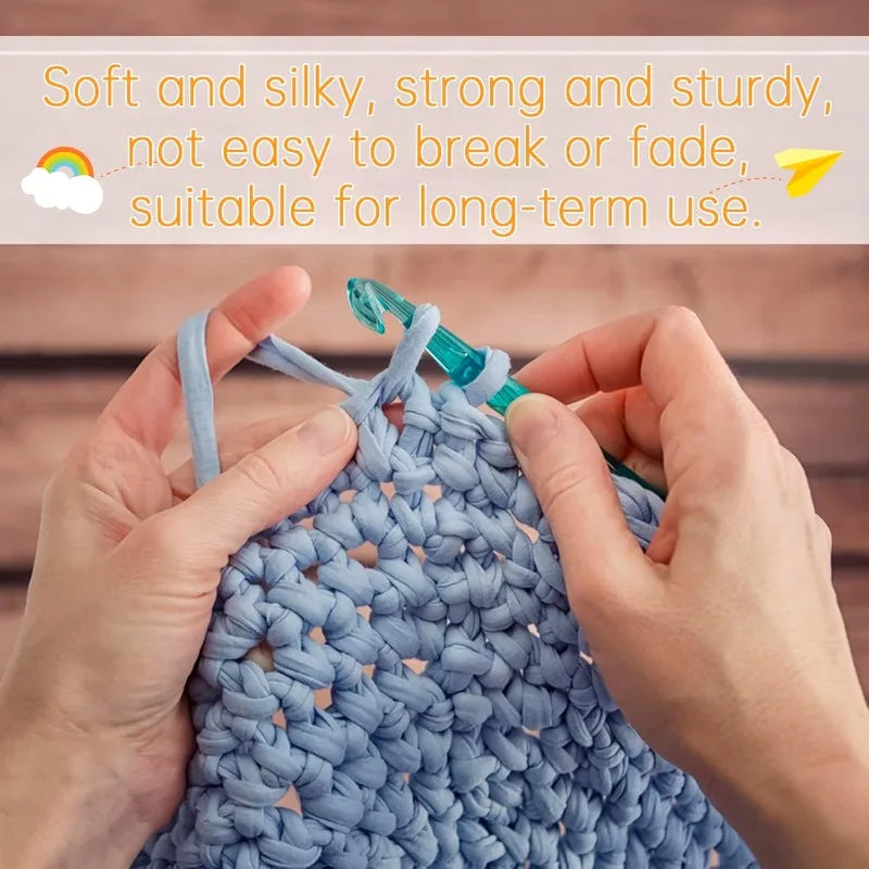 Hands are knitting a light blue crocheted item using thick polyester blended yarn.