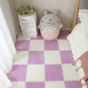 A soft plush white cat-shaped item sits on a purple and white checkered play mat with a paper bag nearby.