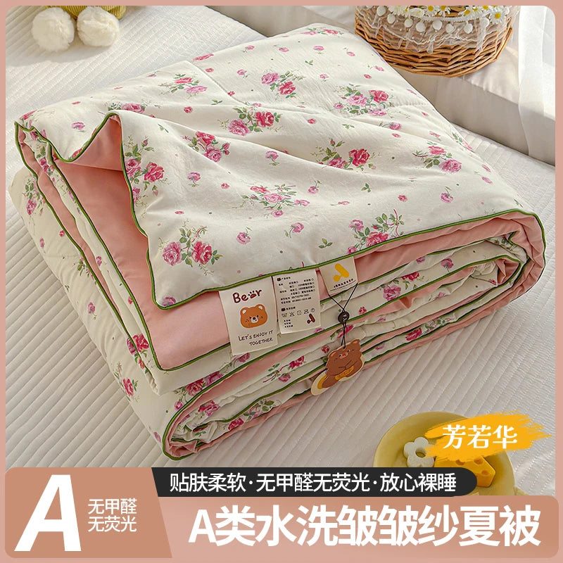 A lightweight summer quilt featuring a cartoon pattern, shown rolled up on a white surface.