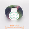 A ball of multi-colored wool yarn with shades of green, purple, and pink.