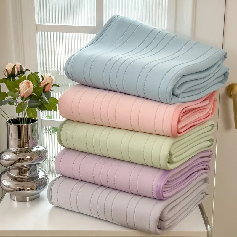 Stack of light blue, pink, and green cooling ice silk bed pads for summer comfort