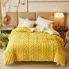 A bright yellow cozy fleece blanket is displayed on a bed with neutral bedding and modern headboard.