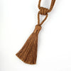 A bundle of golden brown rope tied into a decorative tassel for curtain tiebacks.