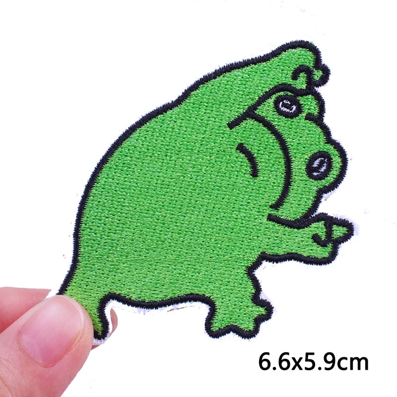 A hand holds a bright green cartoon cat embroidered iron-on patch.