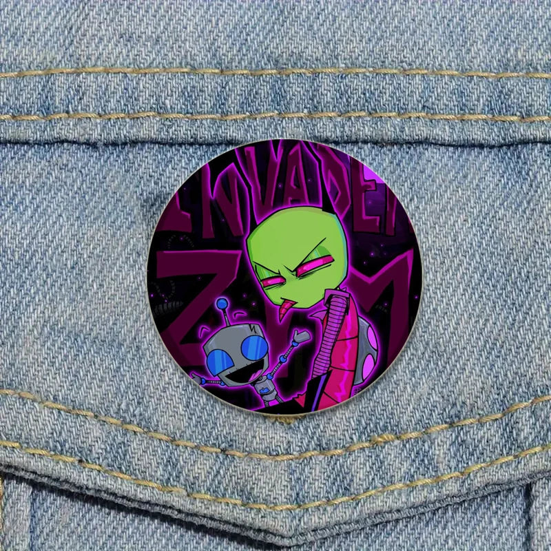 An enamel pin featuring a green, menacing alien character with purple accents and the text Invader ZIM.