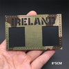 A rectangular tactical patch featuring the word IRELAND in camouflage lettering and two black squares on a green and brown pa