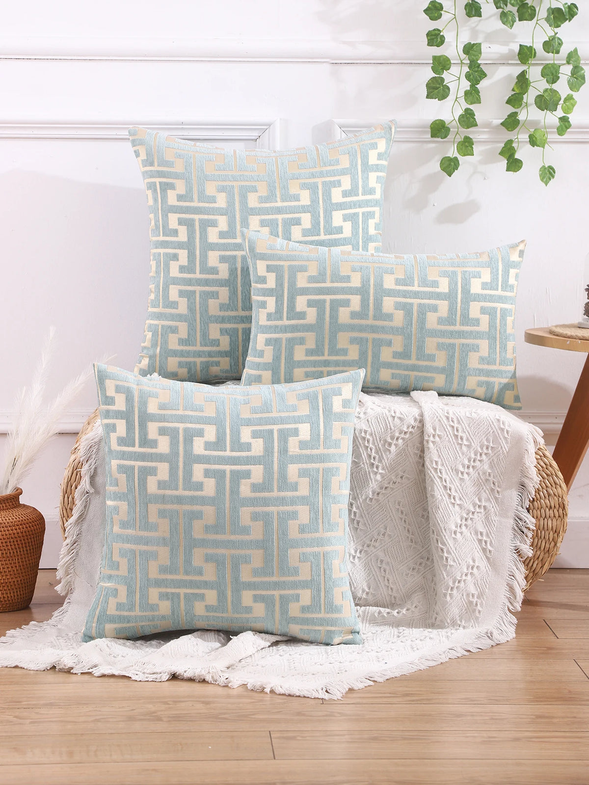 A collection of light blue and beige geometric patterned throw pillows displayed on a white surface.