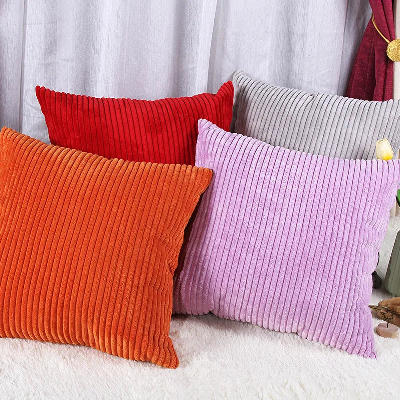 A collection of striped velvet corduroy cushion covers in shades of orange, red, purple, and gray.
