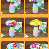 A collection of colorful felt flowers arranged in glass vases with striped fabric stems.