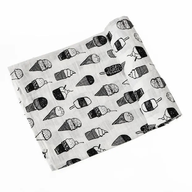 A rolled muslin swaddle blanket featuring a repeating pattern of small, stylized black and white striped objects.
