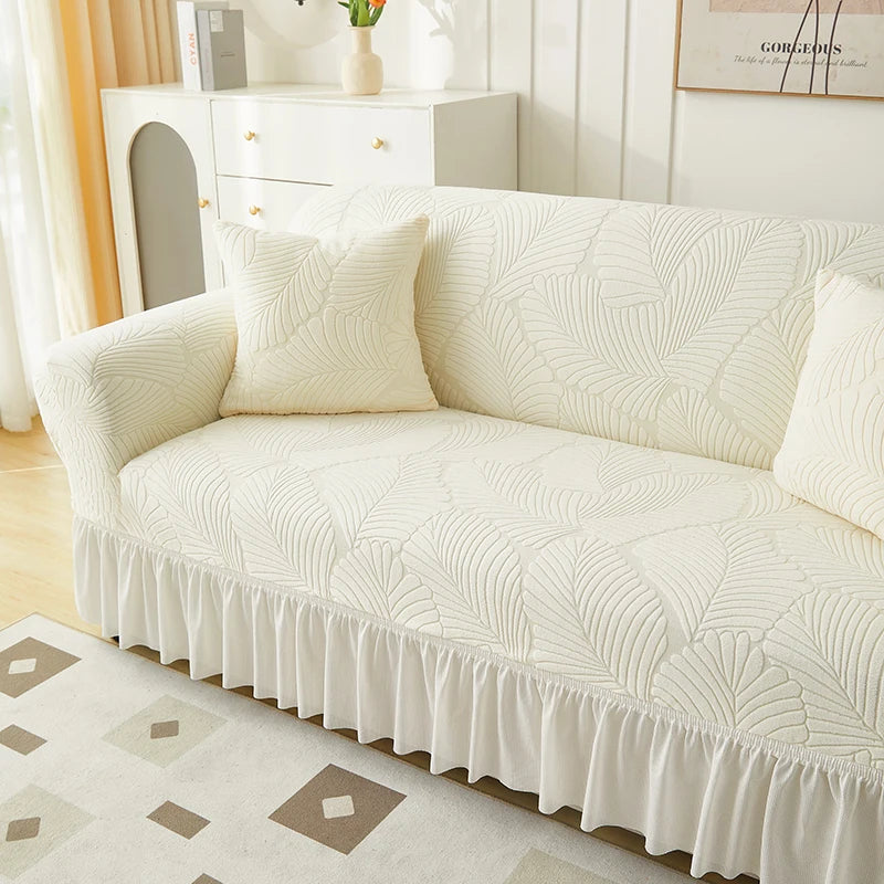 A cream jacquard elastic sofa cover featuring a textured pattern and a ruffled skirt.