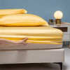 A close-up of a luxury bamboo bedding set featuring bright yellow sheets and pillows on a bed.