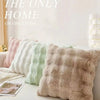 A collection of fluffy winter throw pillow covers in pastel shades are displayed on a white surface.