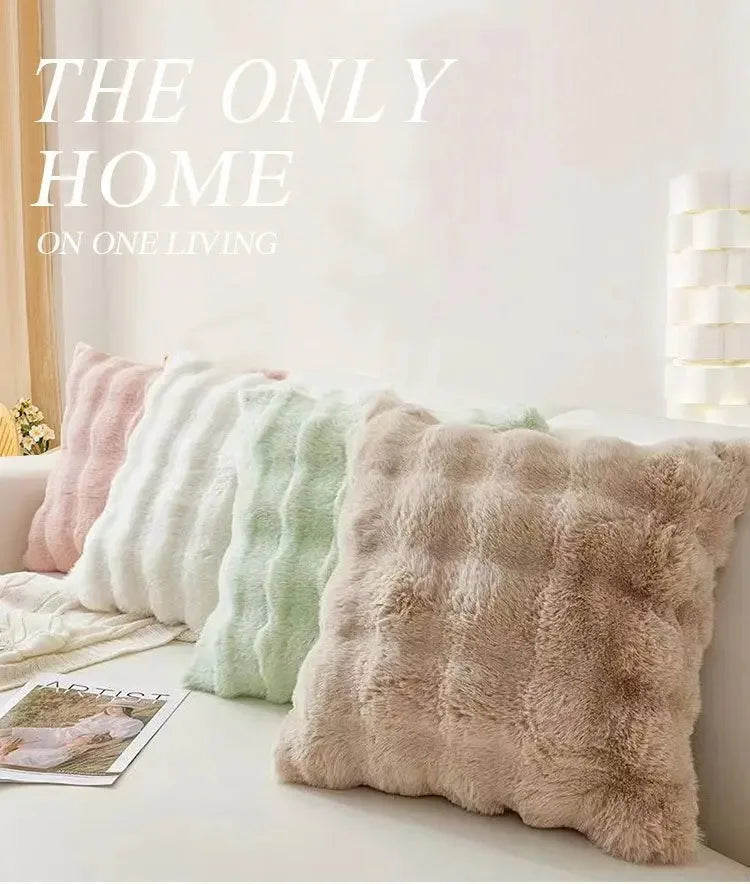 A collection of fluffy winter throw pillow covers in pastel shades are displayed on a white surface.