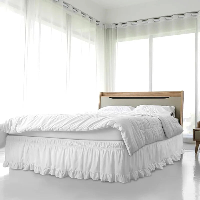 A white ruffled bed skirt is visible beneath a white duvet on a bed in a bright room.