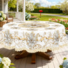 White vintage floral tablecloth displayed on a wooden table outdoors with greenery and white flowers in the background