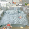 A light blue textured duvet cover set displayed on a bed with pillows and decorative items.