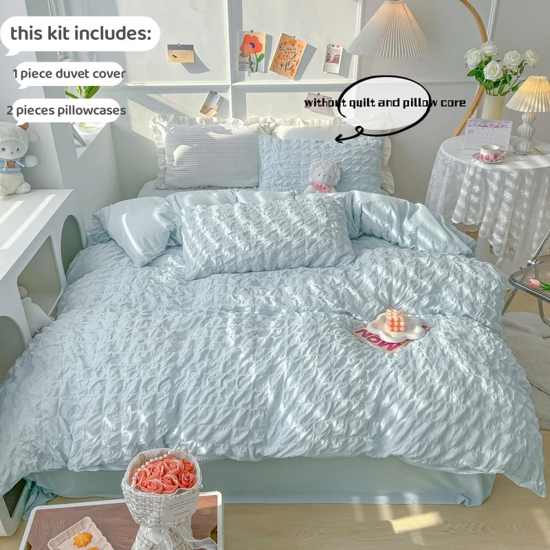 A light blue textured duvet cover set displayed on a bed with pillows and decorative items.