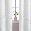 White marble printed curtain panels framing a window with a small green plant.