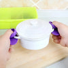 A hand is holding a white silicone pot with a lid, next to a bright yellow silicone product.