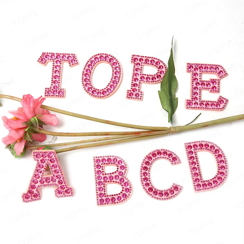 Pink pearl rhinestone letter patches spelling out the alphabet A through E for DIY projects