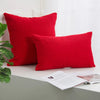 Two red ribbed throw pillows resting on a white surface.