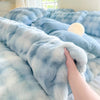 A close-up of a light blue and white fluffy rabbit fleece duvet cover being touched on a bed.