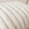 A close-up view of white plush striped decorative pillowcases stacked in a soft, curved arrangement.