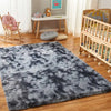 A dark gray and black fluffy shag rug placed on a wooden floor in a bright room.