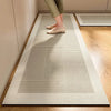 A beige kitchen floor mat with a geometric striped pattern is placed on a wooden floor.