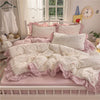 A pink princess style bedding set featuring ruffled sheets and pillows with white floral patterns.