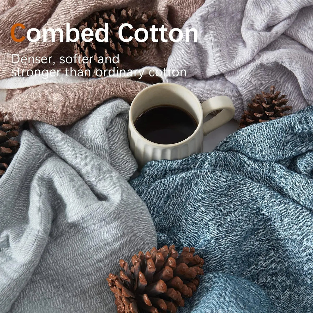A close-up of a textured linen throw blanket in various shades of gray and blue, with a cup of coffee and pine cones.