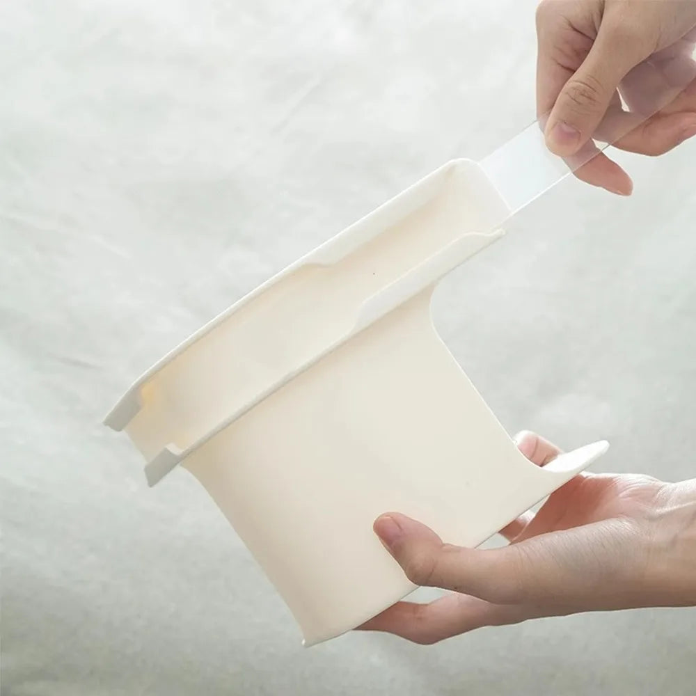 A hand is holding a white invisible bedsheet corner tightener clip, demonstrating its use.