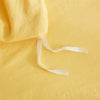 A yellow soft washed duvet cover set with a white drawstring and pom-pom decoration.