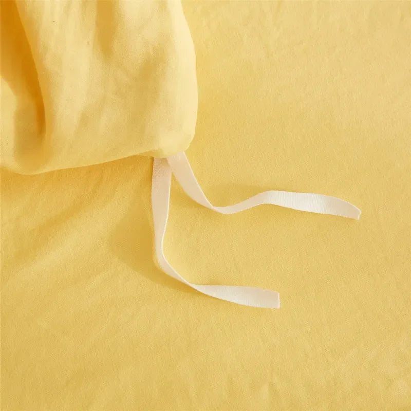 A yellow soft washed duvet cover set with a white drawstring and pom-pom decoration.