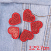 Five red glitter iron-on embroidered love heart star patches placed on a blue denim fabric.