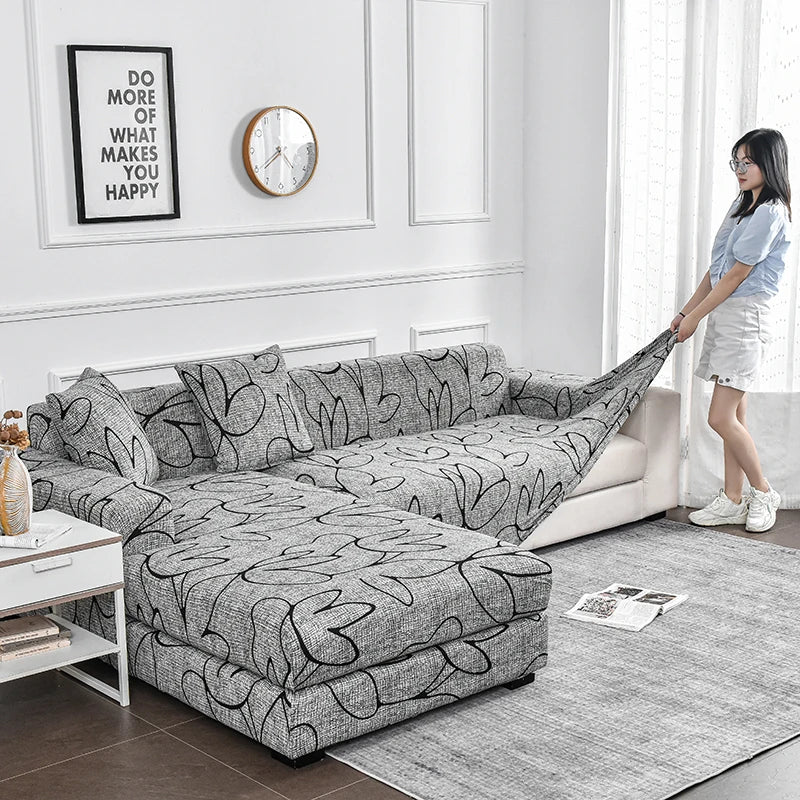 A gray flower print elastic sofa cover protector displayed on a light-colored sofa in a modern living room.