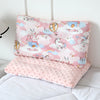 A pink fiber pillow featuring cartoon animals and castles, used for infants.