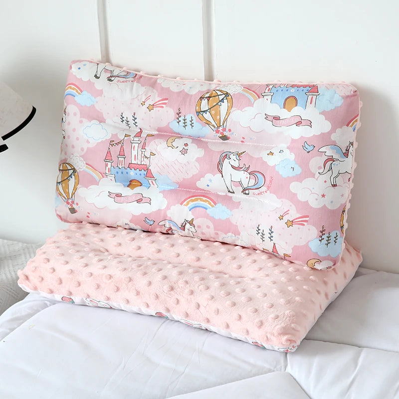 A pink fiber pillow featuring cartoon animals and castles, used for infants.