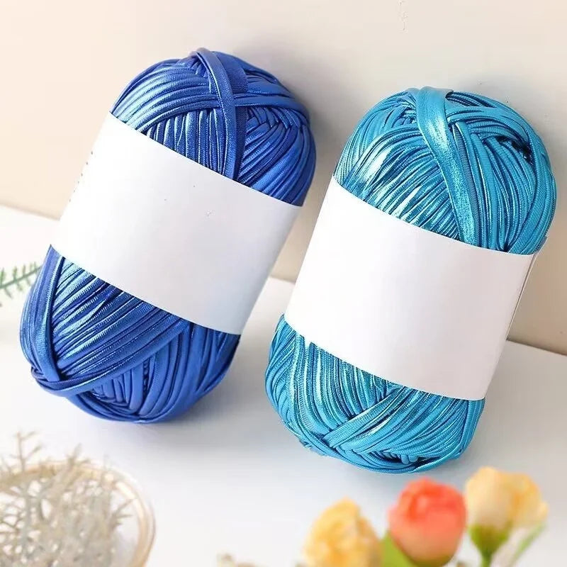 Two skeins of metallic blue fabric strip yarn for crochet and DIY crafts lying on a white surface.