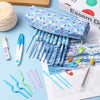 A collection of various ergonomic crochet hooks and knitting needles are displayed on a sheet of paper.