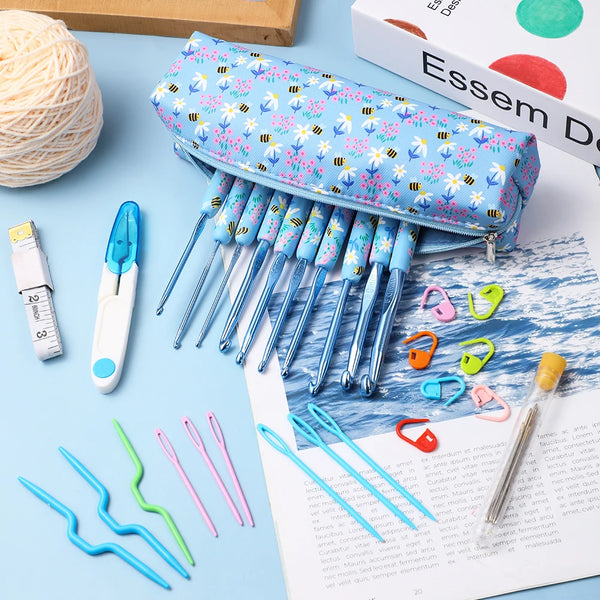 A collection of various ergonomic crochet hooks and knitting needles are displayed on a sheet of paper.