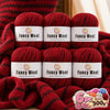 Three skeins of red wool yarn labeled Fancy Wool are displayed on a fabric background.