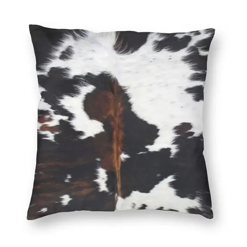 A square cushion cover featuring a black and white cowhide print with a brown accent.