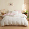 A white duvet cover set with pink accents and pillows on a bed in a bright room.