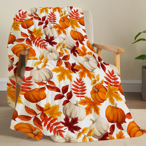 A patterned flannel throw blanket featuring autumn leaves and pumpkins in orange, yellow, and white tones.