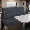 A modern RV dinette featuring a gray striped cushion cover and a white table.